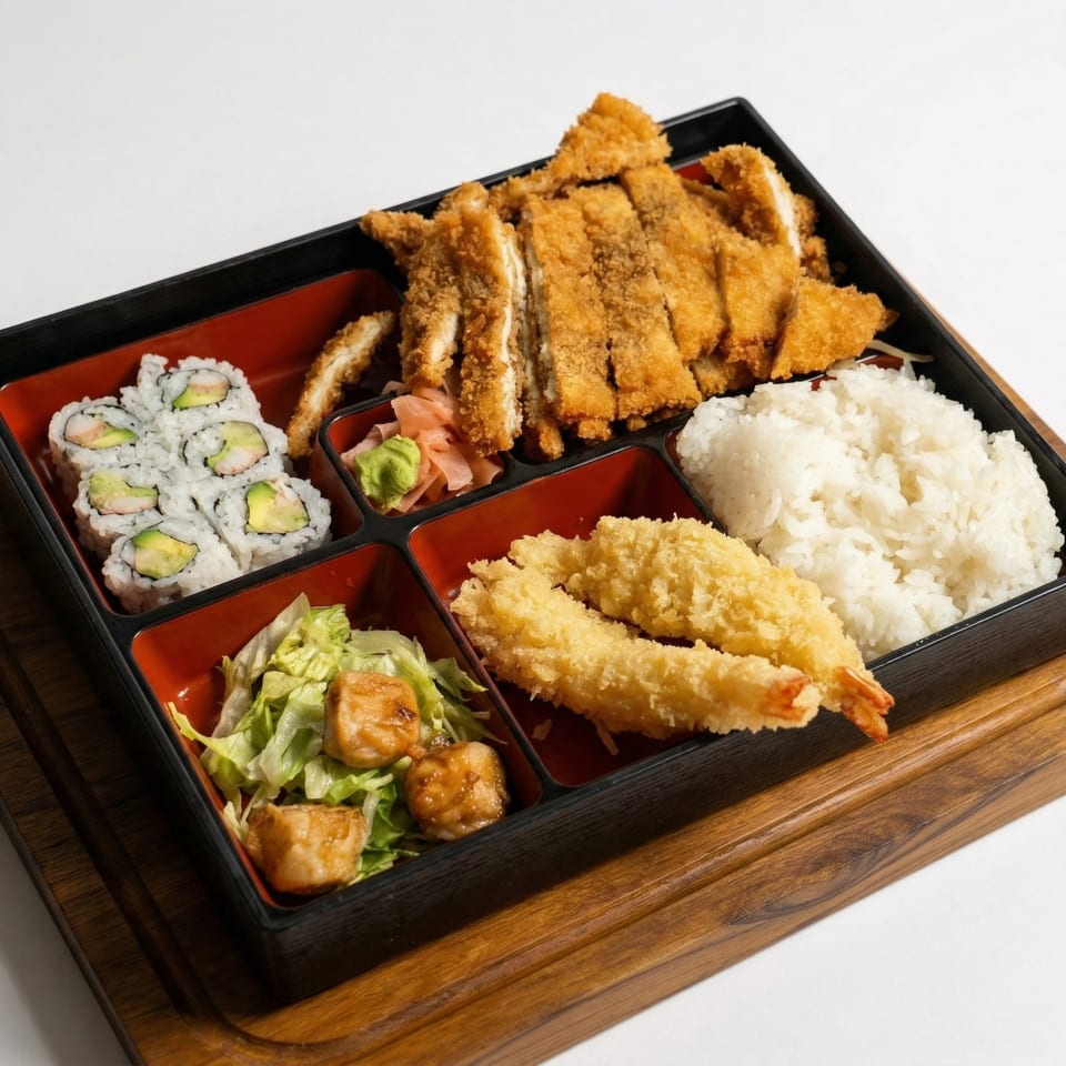 A bento box with chicken katsu, California rolls, tempura shrimp, rice, salad, and pickled ginger.